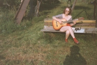 Sedmnáctiletá Iveta poctivě cvičí na zahradě na kytaru.