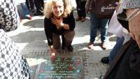 Nora Strejilevich in front of a paving stone carrying the name of her cousin Hugo Daniel Strejilevich and others that were captured at Gutierrez hospital and disappeared (2016)